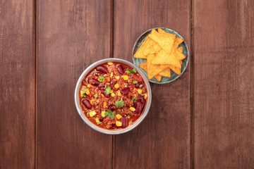 Chili con carne, traditional Mexican dish, overhead photo with nacho chips and copy space