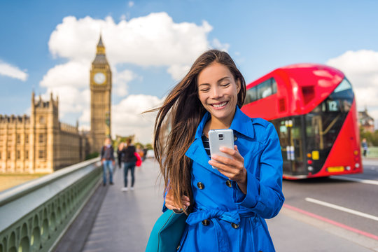 London phone business woman texting on smartphone mobile app for payment or online shopping. Urban city lifestyle Asian girl happy walking on Big Ben and red bus background.