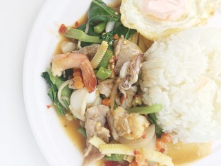 Vegetable stir-fry dishes with spicy  seafood with basil leaves and mixed vegetable and fried egg on jasmine rice in white dish. Thai style food.