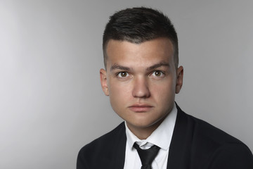 Studio shot of young man looking at the camera on grey background.