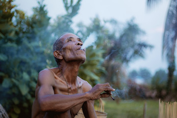 Old man smokes cigarettes.