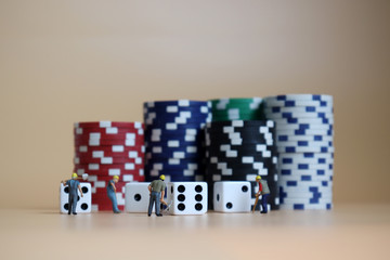 Miniature workers with stacks of casinos chips and dice.