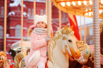 happy kid girl in amusement park on Christmas and New Year Holidays. Moscow Red Square on background