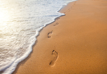 beach, wave and footprints at sunset time