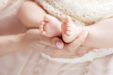 Newborn baby feet in mother hands. Mother holding legs of the kid in hands. Close up image. Happy...