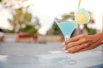 Woman hand with cocktail near swimming pool