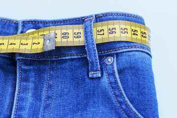 yellow measuring in jeans on a blue background, the concept of losing weight