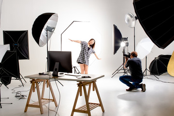 Photographer and pretty model working in modern lighting studio with many kinds of flash and accessories.