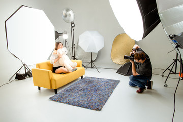Photographer and pretty model working in modern lighting studio with many kinds of flash and...