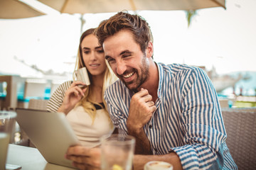 Happy couple checking menu at the tablet