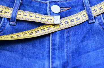 Jeans and measuring tape close-up, concept of healthy lifestyle and losing weight