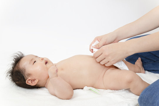 新生児の沐浴後にオムツを付ける方法を説明するマニュアル用写真。裸の赤ちゃんにオムツを当てるイメージ