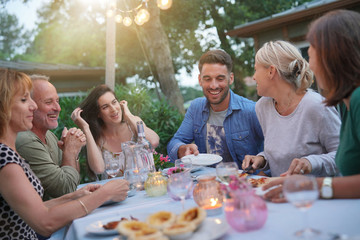 Friends enjoying summer barbecue dinner in garden