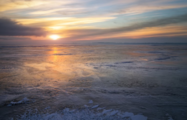 Beautiful colorful winter landscape with frozen lake and sunset sky.