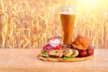 beer in a glass, sausage, vegetables on a table