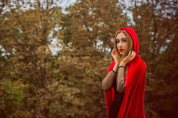  Concept of Halloween. Beautiful and simple costume of little red hood. Mysterious hooded lady figure . Girl in red raincoat. Cosplay Fairy Tale Little Red Riding Hood 