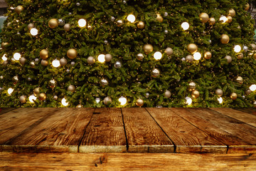 Christmas and New year background with empty wooden deck table over blurred christmas tree at...