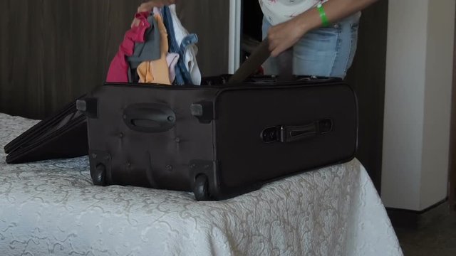 A girl with suitcases in the hotel. The girl is dismantling the suitcase.