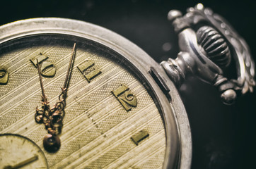 antique pocket watch with vintage golden arrows on the old yellowed dial and clockwork key on a...