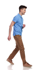 side view of a young casual man walking