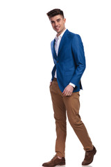 side view of a smiling young casual man stepping forward