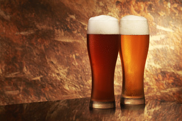 glass of beer with foam on background