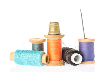 Collection of color thread spools with needle and thimble isolated on white background. Sewing...