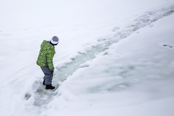the boy is walking on a slippery icy path