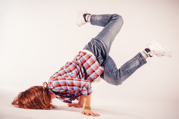 Young beautiful woman doing an element of breakdance dancing hip hop on a light background
