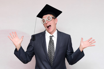 Happy graduate student in graduation cap is dancing isolated on gray background. Education concept.