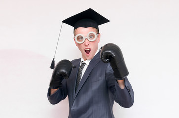 Angry graduate student in the boxing gloves isolated on gray background. Education concept. A protection of diploma work.