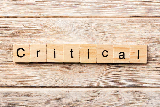 critical word written on wood block. critical text on table, concept