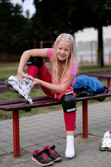 active lifestyle in a modern city - girl puts on roller skates at the stadium
