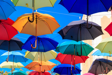 Fototapeta na wymiar Multicolored umbrellas on the city street. The city street is decorated with many colorful open umbrellas