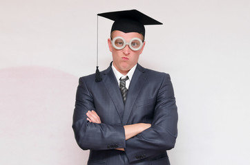 Disgruntled and arrogant graduate student in the cap isolated on gray background. Education concept.