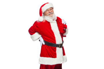 Christmas. Santa Claus is suffering from back pain and holds a red bag with gifts on his back. Isolated on white background.