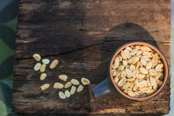 Crunchy, fried and salted peanuts, peeled. A nutritious snack in a small kerimic pot on the...
