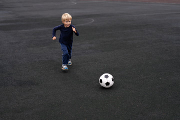 active lifestyle in a modern city - little boy playing with a soccer ball at the stadium