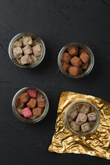 Set of handmade chocolate truffles in cocoa powder in a glass jar on black background