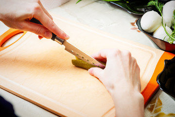 Obraz premium preparing russian salad 'Olivier', chopping the cucumber