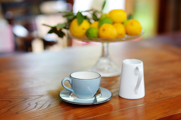 Beautiful blue ceramic teacup on a wooden table, with a dish of lemons on the background.