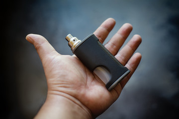 high end unregulated bottom feed squonk box mods with rebuildable dripping atomizer in hand on dark...
