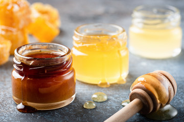 Honey in jar with wooden honey dipper, liquid honey. Closeup view