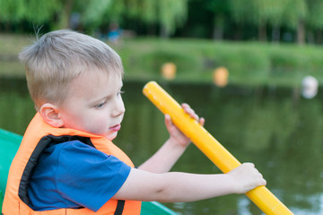 A little boy in a life jacket in a boat.