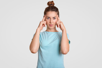 Photo of concentrated young female model tries to focuse on necessary information, keeps both index...