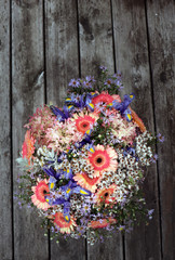 Fototapeta na wymiar Bouguet of colorful flowers from the garden (Gerbera, Iris, Astrangea, Anaphalis, Aster etc.). Bouquet in a vase on an old table.