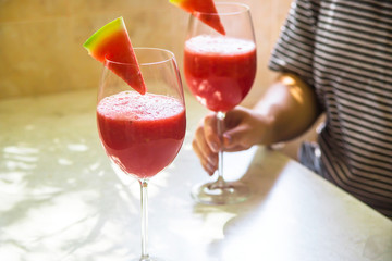 A woman takes a watermelon cocktail from the table in a glass. Fruit cocktails, detox and healthy eating concept