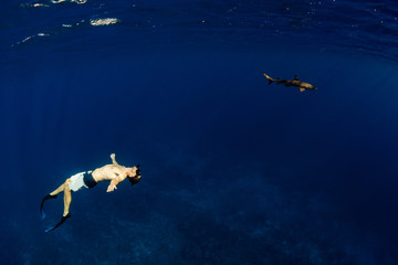 people snorkeling with sharks in blue ocean of polynesia