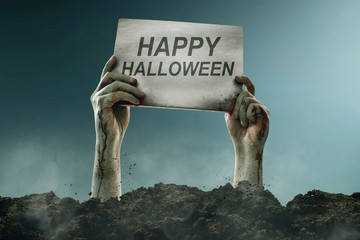 Zombie hands holding halloween sign