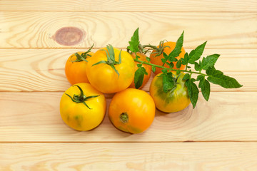 Yellow and orange tomatoes with leaf on a wooden surface